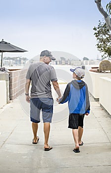 Father and Son walking hand in hand together on the sidewalk