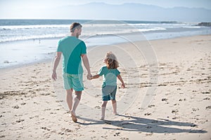 Father and son walking on sea. Dad and child boy holding hands and walk together. Lifestyle and family vacation