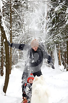 Father and son walking in snowy forest with his beagle dog in pine forest. Family walking with pets and winter outfit