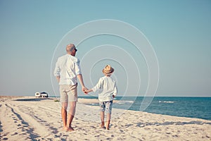 Father and son walks on deserted sea beach not far from their au