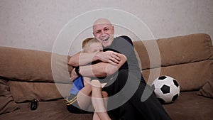 Father and son watch football and shout with happiness when they scored a goal.