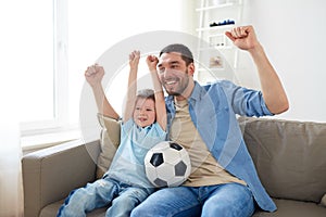 Father and son watching soccer on tv at home