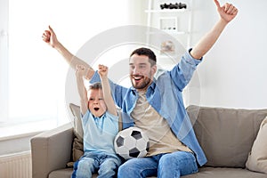 Father and son watching soccer on tv at home