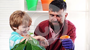 Father and son watering plants in pots. Little boy helping his father to plant. Kids early education.