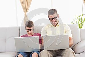 Father and son wearing novelty glasses while using laptop