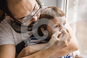 Father and son wiping nose, illness