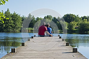 Father and Son on a Wooden Pier on a Pond