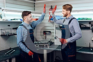 Father and son work at the auto service. Two mechanics work with the details of the car.