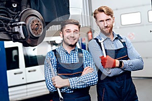 Father and son work at the auto service. Two mechanics work with the details of the car.