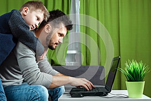 Father and son working on a laptop. Businessman working from home and looking after a child, spending time with a child. The