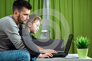 Father and son working on a laptop. Businessman working from home and looking after a child, spending time with a child. The