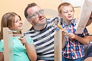 Father and sons are are building the furniture at home