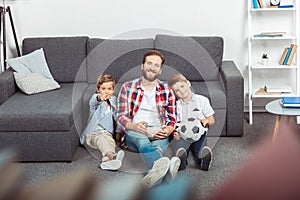 father with sons eating popcorn while watching soccer match