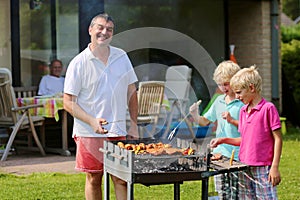 Father with sons grilling meat in the garden photo