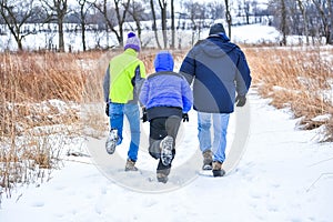 Father and Sons Hiking Through Snow Covered Nature Preserve