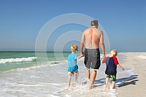 Father and Sons Holding Hands Walking Through Ocean