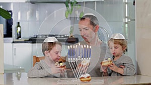 Father and sons with menorah celebrate Hanukkah