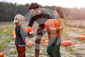 Father and sons in pumpkin patch field