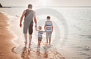 Father and sons walking at the beach at sea