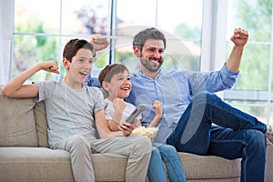 Father and sons watching tv at home photo