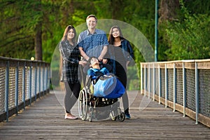 Father standing with biracial children on wooden bridge, special needs