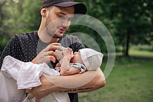 Father standing outside feeding his baby boy with a bottle