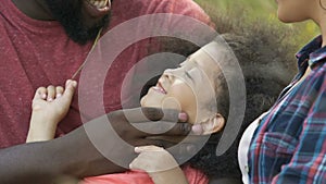 Father stroking child face with love, family relaxing in park on vacation, fun