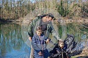 Father with stroller and two children walking along the Aare river in springtime