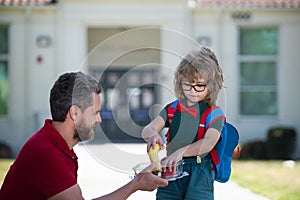 Father supports and motivates son. Kid going to primary school. Little schoolboy eating tasty lunch outdoors. Teachers