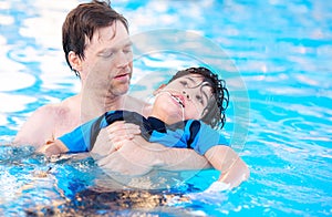 Father swimming in pool with disabled child