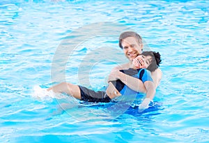 Father swimming in pool with disabled child