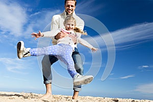 Father Swinging Daughter on Beach