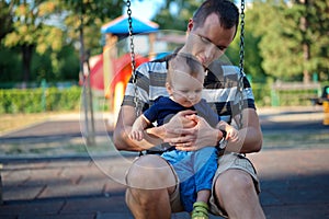Father swinging with his baby on playground