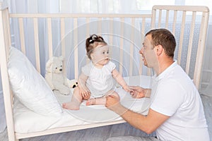 The father talks to the baby or puts him to sleep in the crib in the children`s room