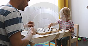 Father teach his child to play chess at home