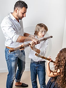 Father teaches children to play bamboo flute