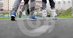 The father teaches the daughter to skate on roller skates.