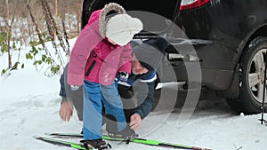 Father teaches daughter to ski. Family holiday in the winter forest.