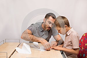 Father teaches his son to do paper airplanes