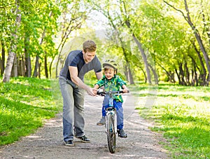 Father teaches his son to ride a bike in park