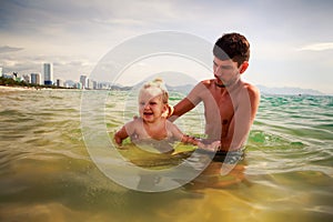 father teaches little daughter to swim in shallow sea water