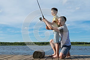 Father teaches son to fish on spinning on the lake on a family day off