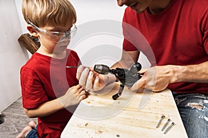 Father teaches son to work with a hand drill.
