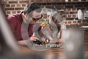 Father teaching daughter to braze at the kitchen table photo