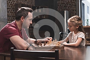 Father teaching daughter to play chess