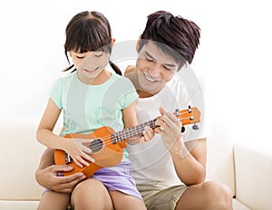 Father Teaching daughter To Play ukulele