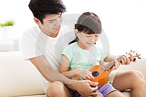 Father Teaching daughter To Play ukulele