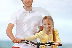 Father teaching daughter to ride bike