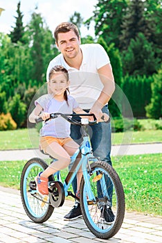 Father teaching daughter to ride a bike