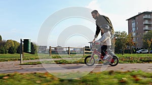 Father teaching daughter to ride bike at urban park. Child girl learning biking with the dad`s help.Family and childhood